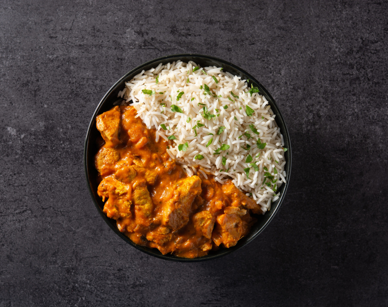 Indian butter chicken in black bowl on black background